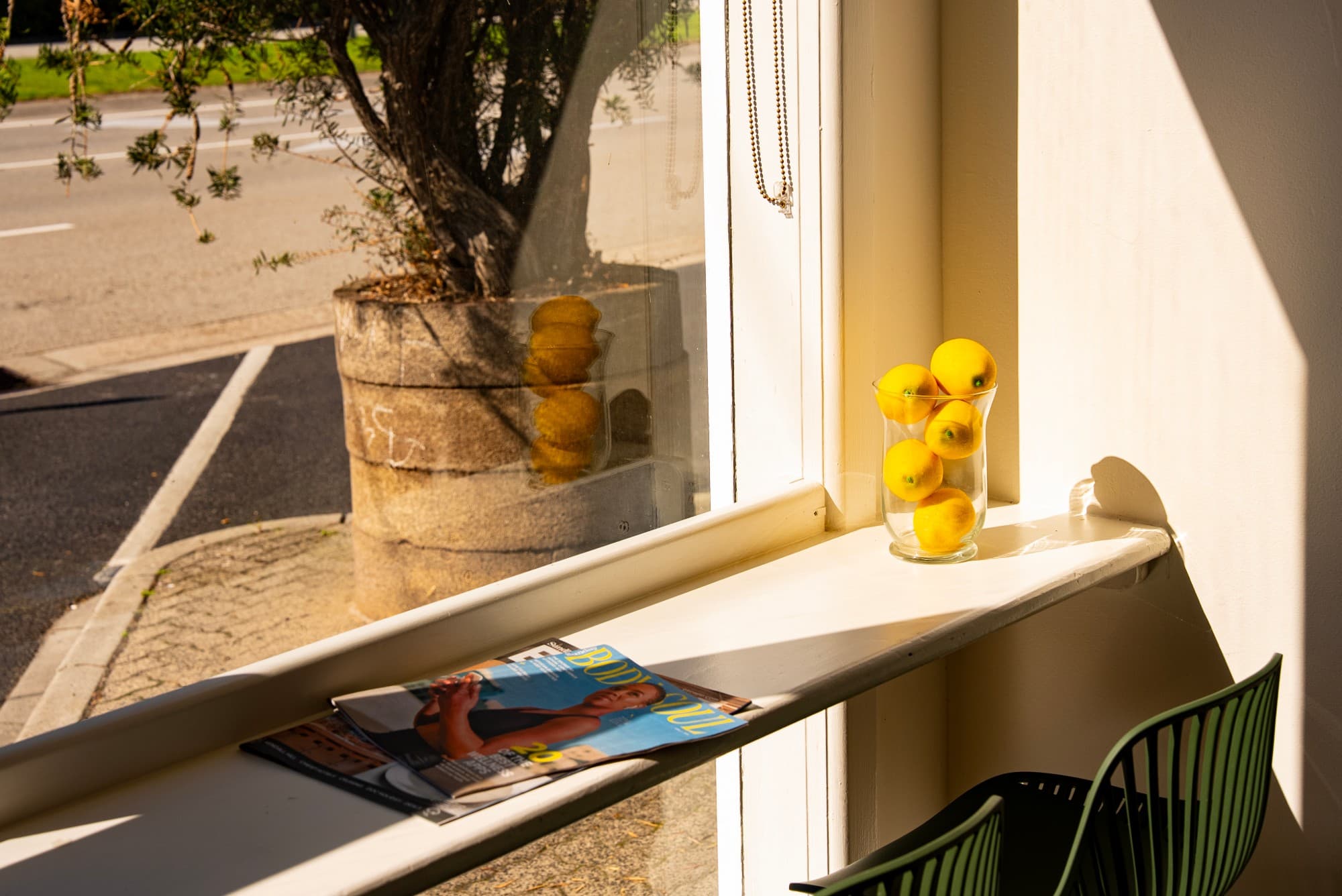 Sunlit café window counter with a glass of lemons and magazines