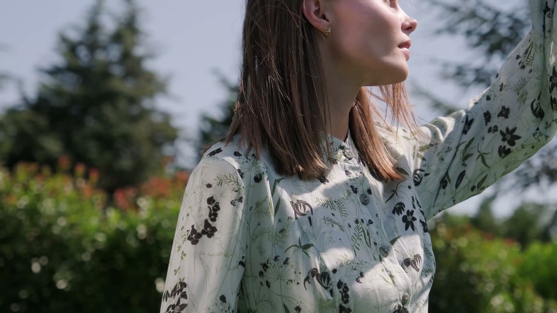Woman in a floral blouse in a sunlit garden, the opening shot of the showreel